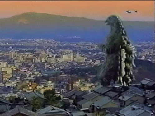 A Giant Monster Is Standing On Top Of A Rooftop Overlooking A City GIF