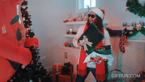 A Gif From Gifrun.com Shows A Man In A Santa Hat Opening Presents GIF