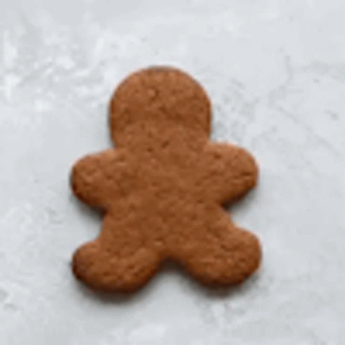 A Gingerbread Man Is Being Decorated With White Frosting . GIF