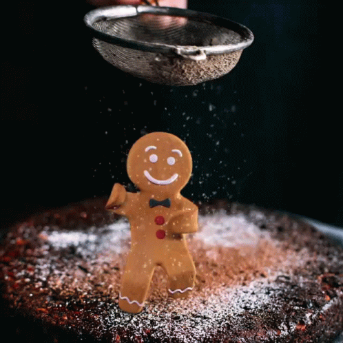 A Gingerbread Man Is Being Sprinkled With Powdered Sugar On A Cake GIF