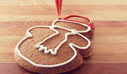 A Gingerbread Man Is Decorated With White Frosting And A Red Ribbon GIF