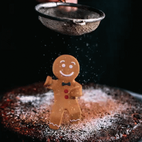 A Gingerbread Man With A Bow Tie Is Being Sprinkled With Powdered Sugar GIF