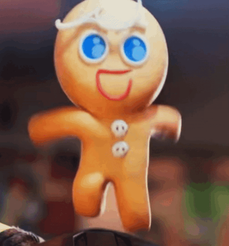 A Gingerbread Man With Blue Eyes Is Jumping In The Air While Standing On A Table . GIF