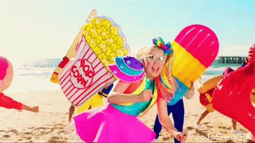 A Girl Holding A Popcorn Bucket On A Beach GIF