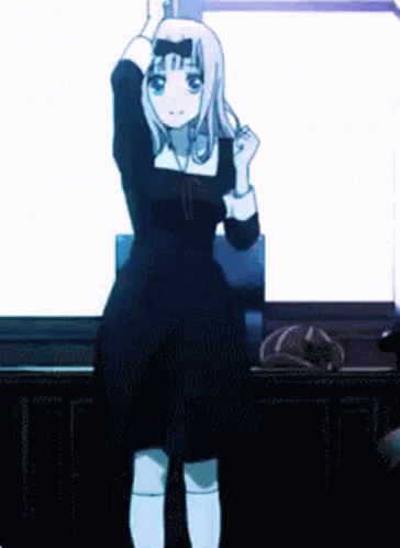 A Girl In A Black Dress Is Standing In Front Of A White Wall . GIF