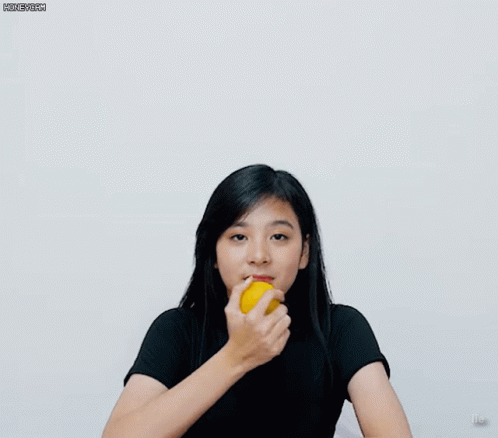 A Girl In A Black Shirt Is Holding A Yellow Object GIF