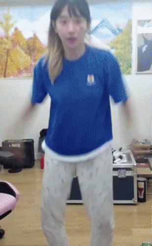A Girl In A Blue Shirt And White Pants Is Dancing GIF