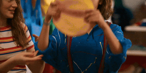A Girl In A Blue Shirt Is Holding A Yellow Ball GIF