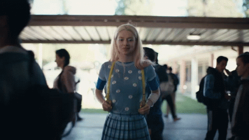 A Girl In A Blue Top And Plaid Skirt Is Holding A Yellow Ribbon GIF