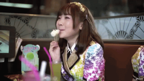 A Girl In A Colorful Outfit Is Eating A Piece Of Cake GIF