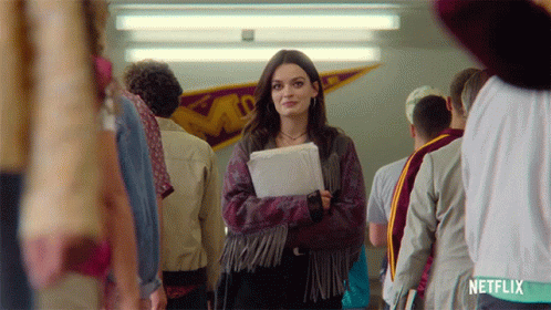 A Girl In A Fringed Jacket Is Standing In A Hallway With Netflix Written On The Bottom GIF