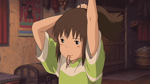 A Girl In A Green Shirt Holds Her Hair Up In A Room GIF
