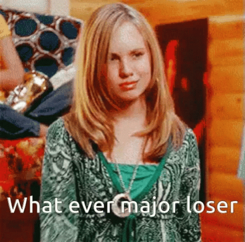 A Girl In A Green Shirt Is Standing In Front Of A Sign That Says What Ever Major Loser GIF