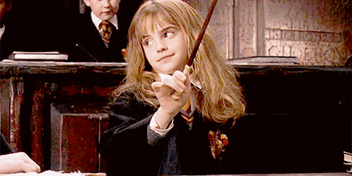 A Girl In A Harry Potter Uniform Is Holding A Wand In Her Hand GIF
