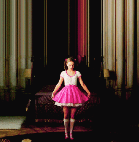 A Girl In A Pink Dress Is Standing In A Room GIF