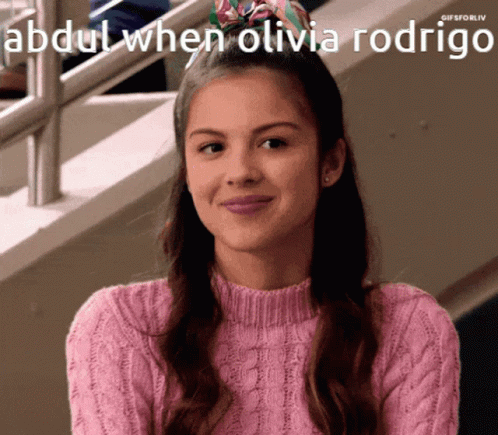 A Girl In A Pink Sweater Is Smiling With The Caption Abdul When Olivia Rodrigo Above Her GIF