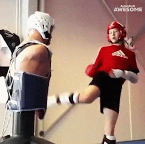 A Girl In A Red Adidas Shirt Kicking A Man In A Helmet GIF