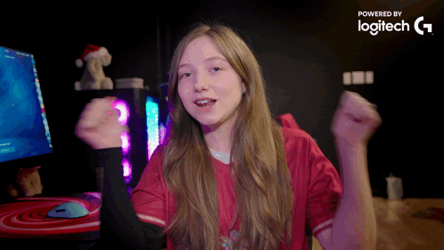 A Girl In A Red Shirt Is Dancing In Front Of A Computer Monitor Which Is Powered By Logitech G GIF