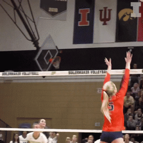 A Girl In A Red Shirt With The Number 5 On The Back Is Jumping Over A Volleyball Net GIF