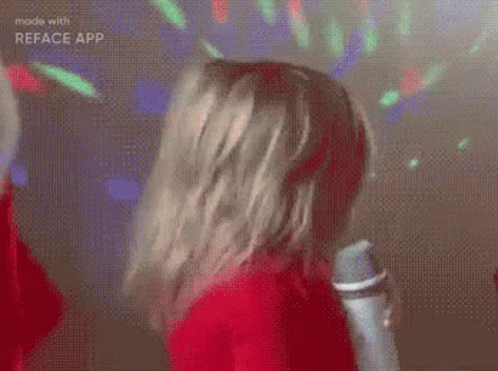 A Girl In A Red Sweater Is Holding A Microphone And Singing . GIF