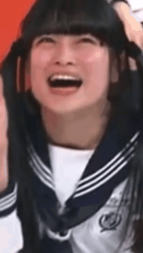 A Girl In A Sailor Uniform Is Laughing And Holding Her Hair GIF