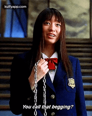 a girl in a school uniform is holding a chain around her neck .