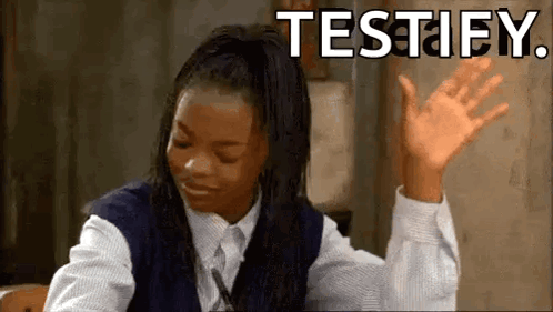 A Girl In A School Uniform Is Sitting At A Desk With Her Hands In The Air And The Words Testify Written Above Her . GIF