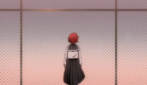 A Girl In A School Uniform Stands Behind A Chain Link Fence GIF