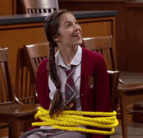 A Girl In A School Uniform Tied Up With Yellow Rope GIF