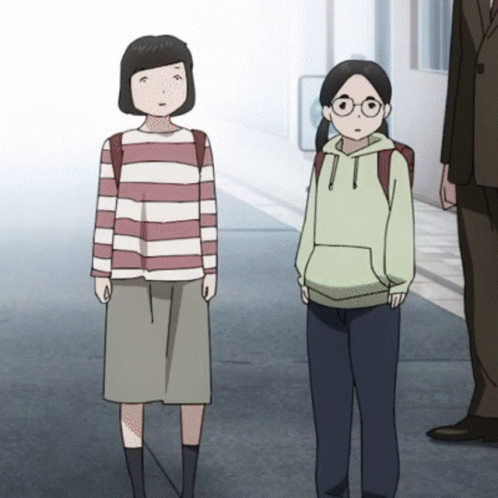A Girl In A Striped Shirt And A Girl In A Green Hoodie Are Standing Next To Each Other On A Sidewalk GIF