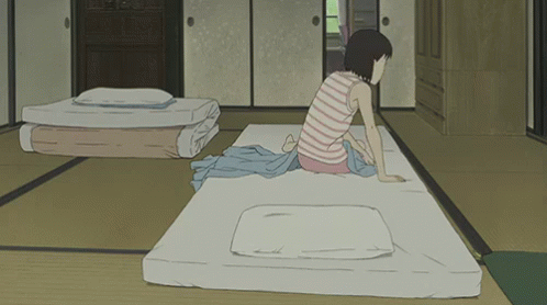 A Girl In A Striped Shirt Sits On A Mattress In A Room GIF