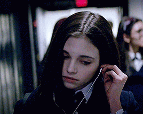 A Girl In A Suit And Tie Is Listening To Music GIF