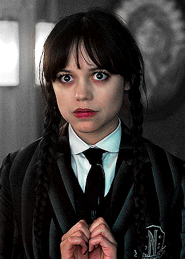 A Girl In A Suit And Tie With The Letter M On Her Sleeve GIF