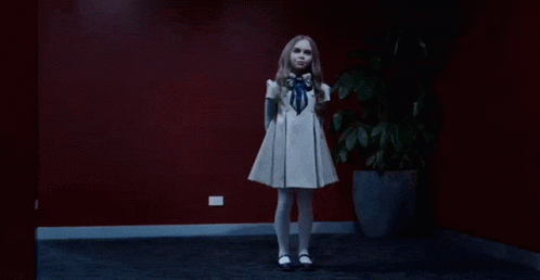 A Girl In A White Dress Is Dancing In A Dark Room GIF