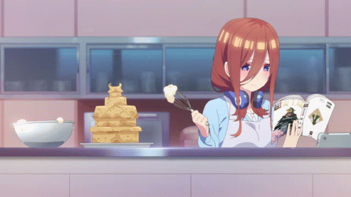 A Girl In An Apron Is Reading A Magazine While Cooking GIF
