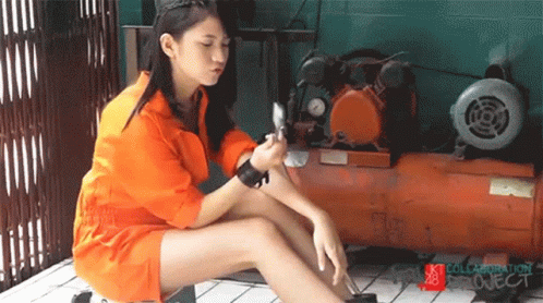 A Girl In An Orange Jumpsuit Sits Next To An Air Compressor With The Words Collaboration Project On The Bottom GIF