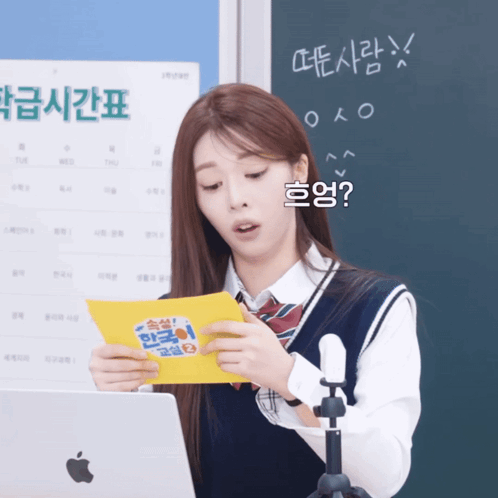 A Girl In Front Of An Apple Laptop Holds A Yellow Piece Of Paper GIF