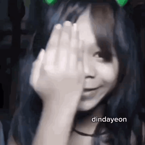 A Girl Is Covering Her Face With Her Hand And Smiling . GIF