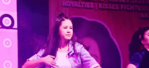 A Girl Is Dancing On A Stage In Front Of A Sign That Says `` Royalties Kisses Fight '' . GIF