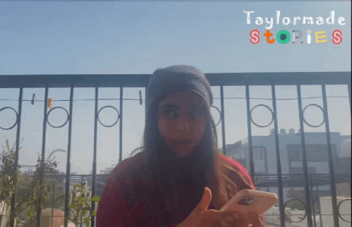 A Girl Is Holding A Cell Phone In Front Of A Taylormade Stories Banner GIF