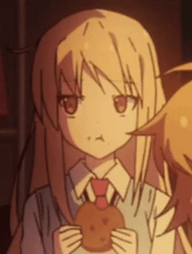 A Girl Is Holding A Cookie In Her Hands And Making A Face . GIF