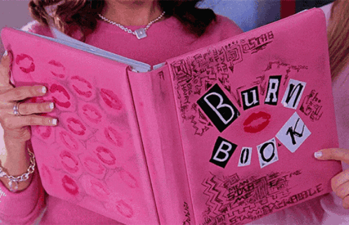 A Girl Is Holding A Pink Burn Book With Kisses On It GIF