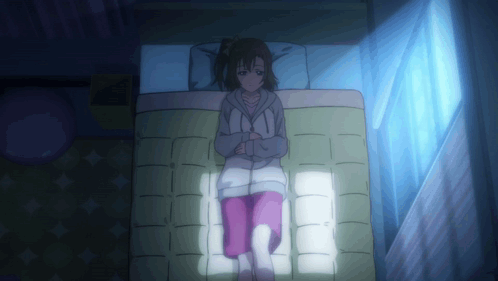 A Girl Is Laying On A Bed With A Blue Light Shining On Her GIF