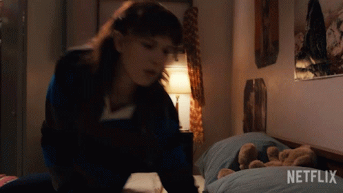 A Girl Is Laying On A Bed With A Teddy Bear And A Netflix Logo In The Corner . GIF