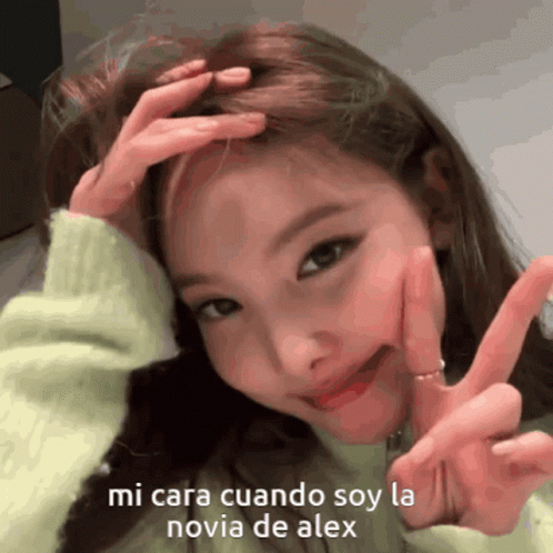 A Girl Is Making A Peace Sign With Her Hands On Her Head GIF