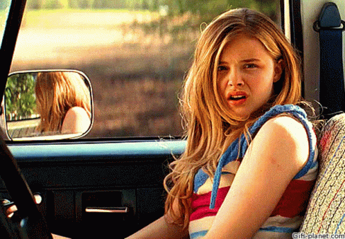 A Girl Is Sitting In The Back Seat Of A Car With A Surprised Look On Her Face .. GIF