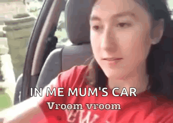 A Girl Is Sitting In The Driver 'S Seat Of A Car . GIF