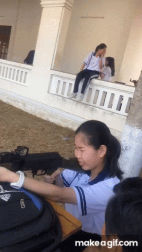 A Girl Is Sitting On A Balcony Talking To Another Girl With Make A Gif.com Written Below Her GIF