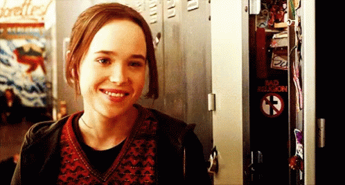 A Girl Is Smiling In Front Of A Locker That Says Bad Religion On It GIF