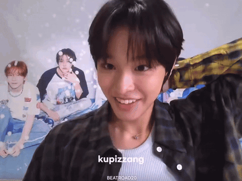 A Girl Is Smiling In Front Of A Poster That Says Kupizzang On It GIF